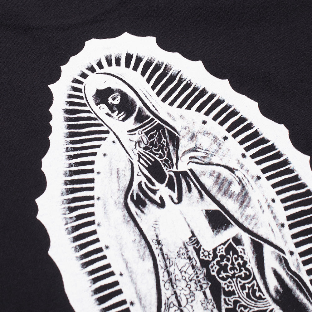 Detailed macro studio close-up of the back graphic on the Wacko Maria Washed Heavy Weight T-Shirt, focusing on the intricate linework, radiant sunburst halo, star-patterned cloak, and praying hands of the white Virgin Mary screen print on textured black cotton jersey.