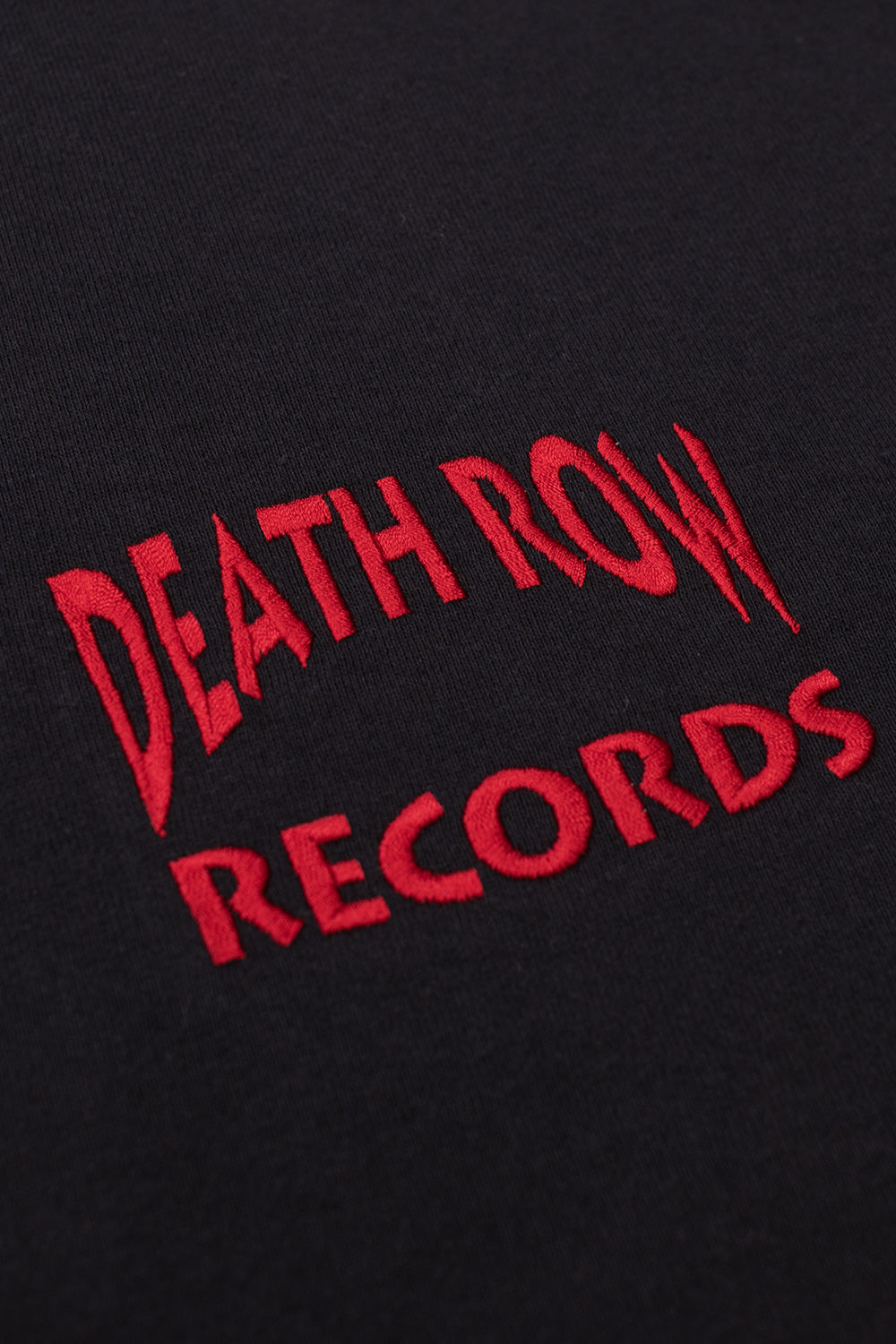 Detailed close-up of the vibrant red embroidered Death Row Records logo on the chest of the black t-shirt.
