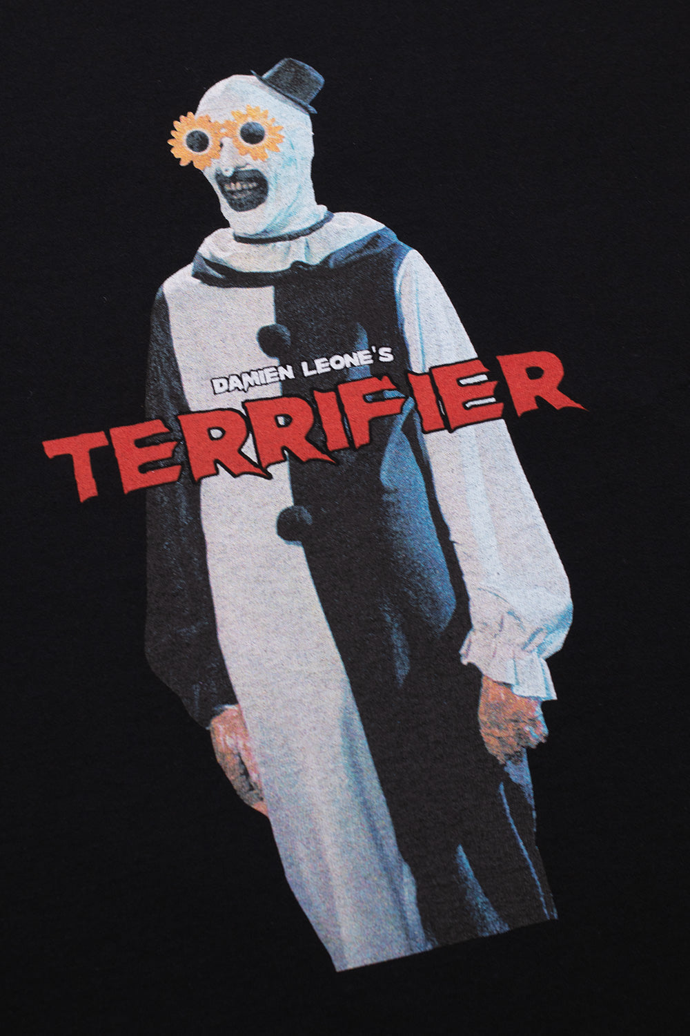 Close-up of Art the Clown wearing flower sunglasses print on Wacko Maria x Terrifier T-shirt, Damien Leone horror movie graphic with bold Terrifier logo