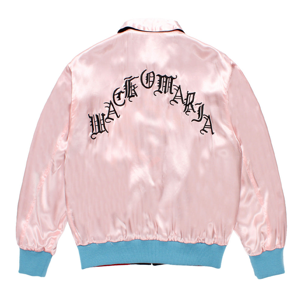 Back studio flat lay view of the reversed pale pink silky satin side of the Wacko Maria x True Romance Ska Jacket, highlighting the gathered light blue ribbed knit hem and cuffs and bold arched black Old English gothic lettering spelling out "WACKO MARIA" across the upper shoulders.