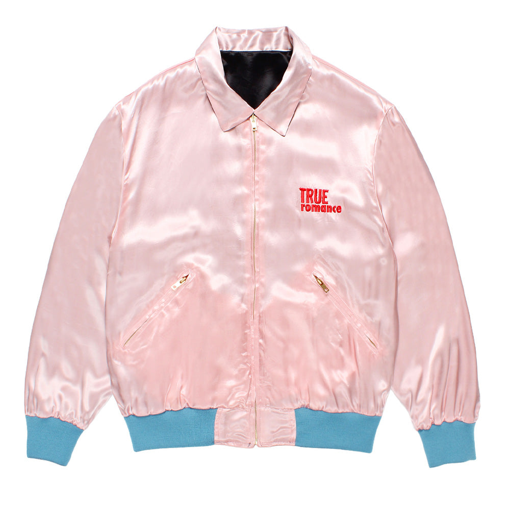 Front flat lay studio view of the pink satin side of the reversible Wacko Maria x True Romance Ska Jacket, detailing the classic collar, gold front zip closure, slanted zippered slash pockets, pastel blue elasticized rib-knit trims, and red embroidered "TRUE ROMANCE" chest logo.